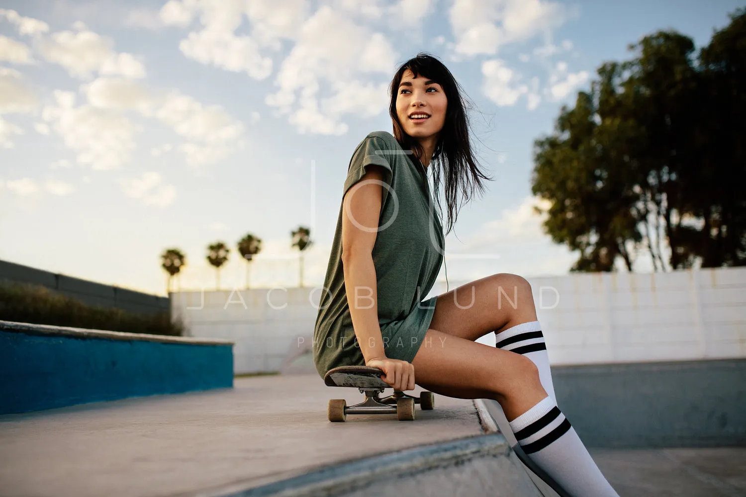 Beautiful skateboarder sitting at skate park